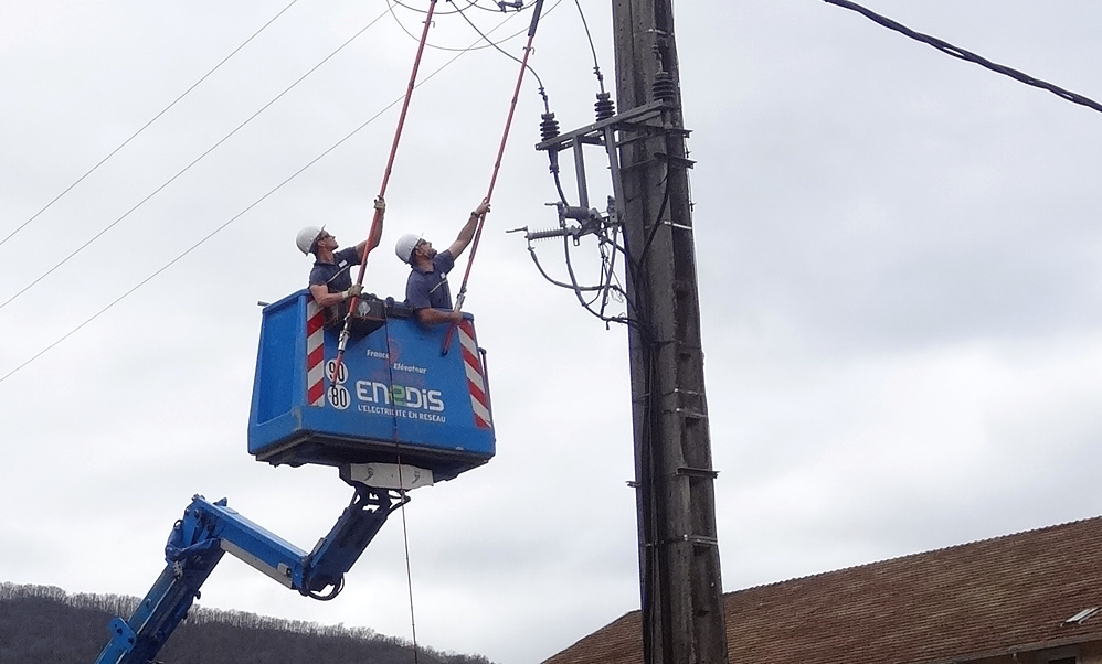 Deux techniciens d'Enedis interviennent sur une ligne haute tension.